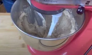 Stand mixer blending dough in a stainless steel bowl on wooden surface. Perfect for baking enthusiasts.